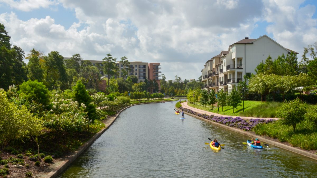 People kayaking and paddleboarding along The Woodlands Waterway