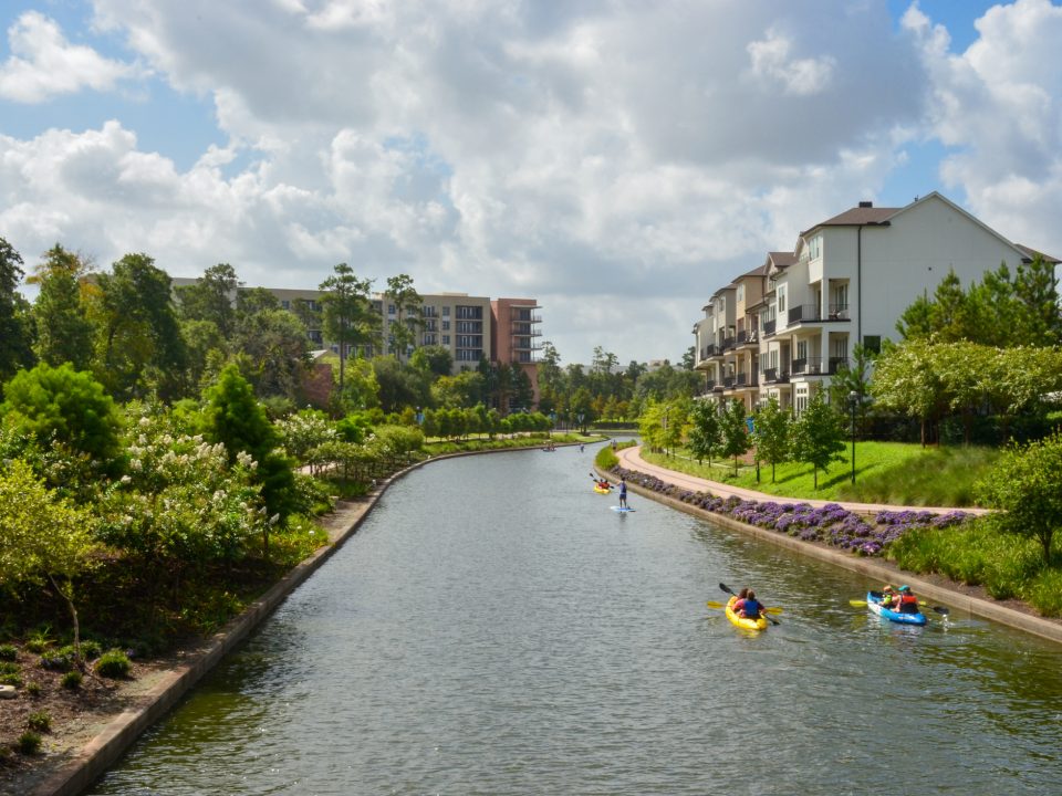 People kayaking and paddleboarding along The Woodlands Waterway